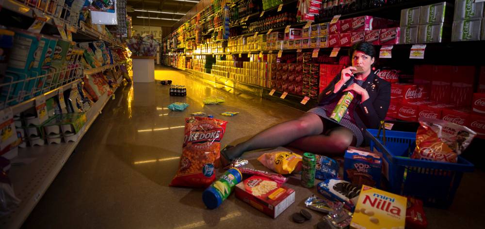 Woman lying on flower in supermarket eating crackers